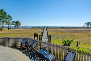 A wooden deck with lounge chairs and a pathway leading to a beach. - Family-friendly, beachfront getaway with a stainless kitchen & shared pool (Dauphin Island)