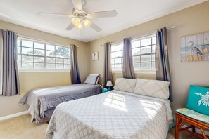 A bedroom with two beds, a ceiling fan, and large windows with curtains. - Family-friendly, beachfront getaway with a stainless kitchen & shared pool (Dauphin Island)