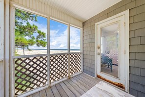 Eine überdachte Veranda mit Blick auf den Strand, ein Gitter und eine Tür zu einem Innenbereich.