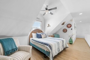 Ein Schlafzimmer mit Bett, Stuhl, Deckenventilator, Fenster und Wanddekorationen.