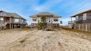 Uma propriedade à beira-mar com uma casa principal, duas construções menores e uma praia de areia.