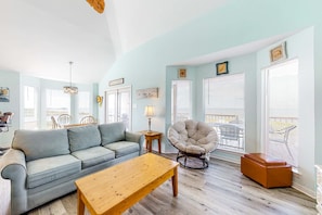 A living room with a sofa, a wooden coffee table, a chair, and a window with blinds. - Dog-friendly beach house with fantastic location, access to water (Dauphin Island)