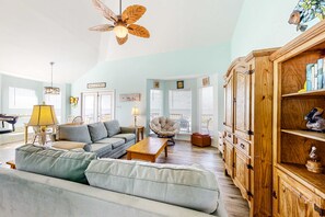 A spacious living room with a sofa, armchairs, a wooden cabinet, and a ceiling fan. - Dog-friendly beach house with fantastic location, access to water (Dauphin Island)