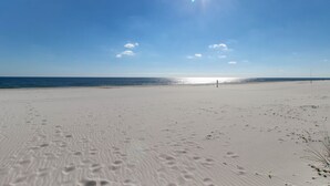 A beach with footprints, a clear sky, and the ocean in the background. - Bright beachfront condo with 2 Gulf-side pools, tennis courts & fitness room (Orange Beach)