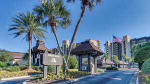 A hotel entrance with a sign reading 'ROMAR HOUSE,' palm trees, and a clear blue sky. - Bright beachfront condo with 2 Gulf-side pools, tennis courts & fitness room (Orange Beach)