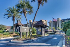 A hotel entrance with a sign reading 'ROMAR HOUSE,' palm trees, and a clear blue sky. - Bright beachfront condo with 2 Gulf-side pools, tennis courts & fitness room (Orange Beach)