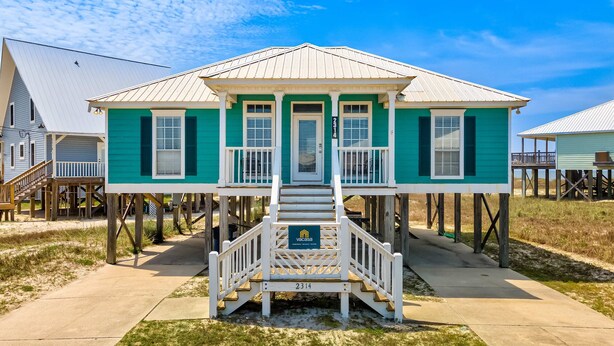 A two-story house with a porch, a staircase, and a number sign. - Newly remodeled bay view home with high-speed WiFi, central AC, and gas grill (Dauphin Island)