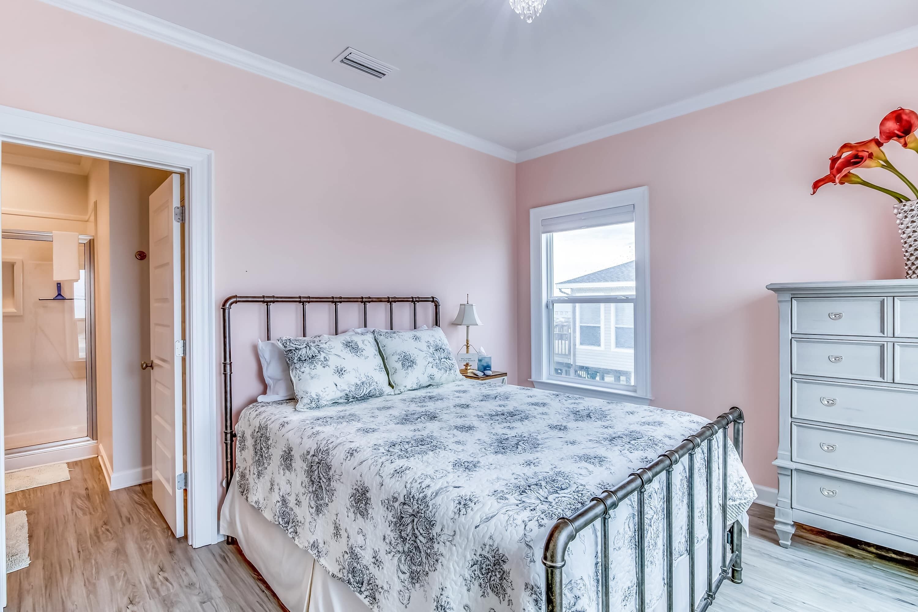 A bedroom with a bed, dresser, window, and door.
