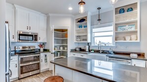 Una cocina moderna con armarios blancos, electrodomésticos de acero inoxidable, una isla grande y vistas de la ciudad.