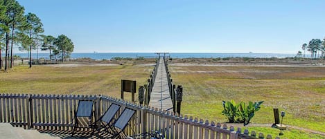 A wooden deck with lounge chairs and a view of the beach.