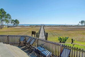 A wooden deck with lounge chairs and a view of the beach. - Condo with WiFi, boardwalk to beach, Gulf view, pool, & picnic area (Dauphin Island)