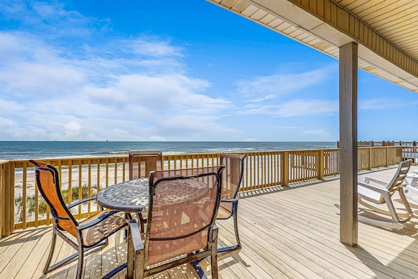 A wooden deck with a round table and chairs, overlooking the ocean. - Charming beachfront home with Gulf views & wraparound deck - right on the sand (Dauphin Island)