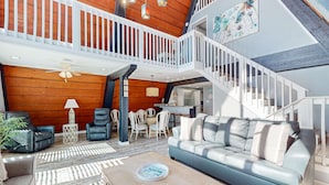 Ein geräumiger Wohnbereich mit hoher Decke, einer Treppe und Blick zur Küche.