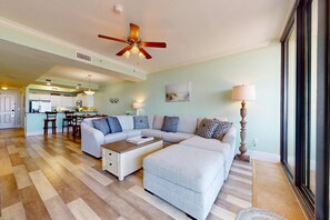 A spacious living room with a sectional sofa, a coffee table, and a ceiling fan. - Beachfront condo with pool, private balcony, and laundry (Dauphin Island)