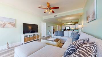 A living room with a sofa, a coffee table, a TV, and a ceiling fan.