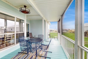 A covered outdoor area with a table and chairs, a ceiling fan, and a view of a grassy area. - Two-story, dog-friendly home with partial ocean views, decks, private washer,dryer (Dauphin Island)