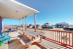A wooden deck with a covered seating area, overlooking a beach with dunes and beach huts. - Dog-friendly home with Gulf views, washer,dryer & central AC (Dauphin Island)