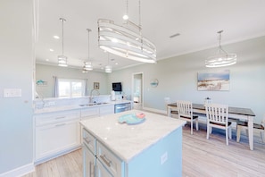 A modern kitchen with white cabinets, a marble island, and pendant lighting. - Dog-friendly home with Gulf views, washer,dryer & central AC (Dauphin Island)