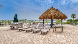 A rooftop lounge area with lounge chairs, a table, and a thatched umbrella. - Beachview condo with lazy river, marina, multiple pools and internet (Orange Beach)