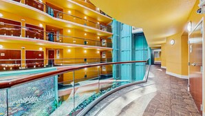 A multi-level hotel interior with a glass railing, a curved floor design, and a blue elevator. - Beachview condo with lazy river, marina, multiple pools and internet (Orange Beach)