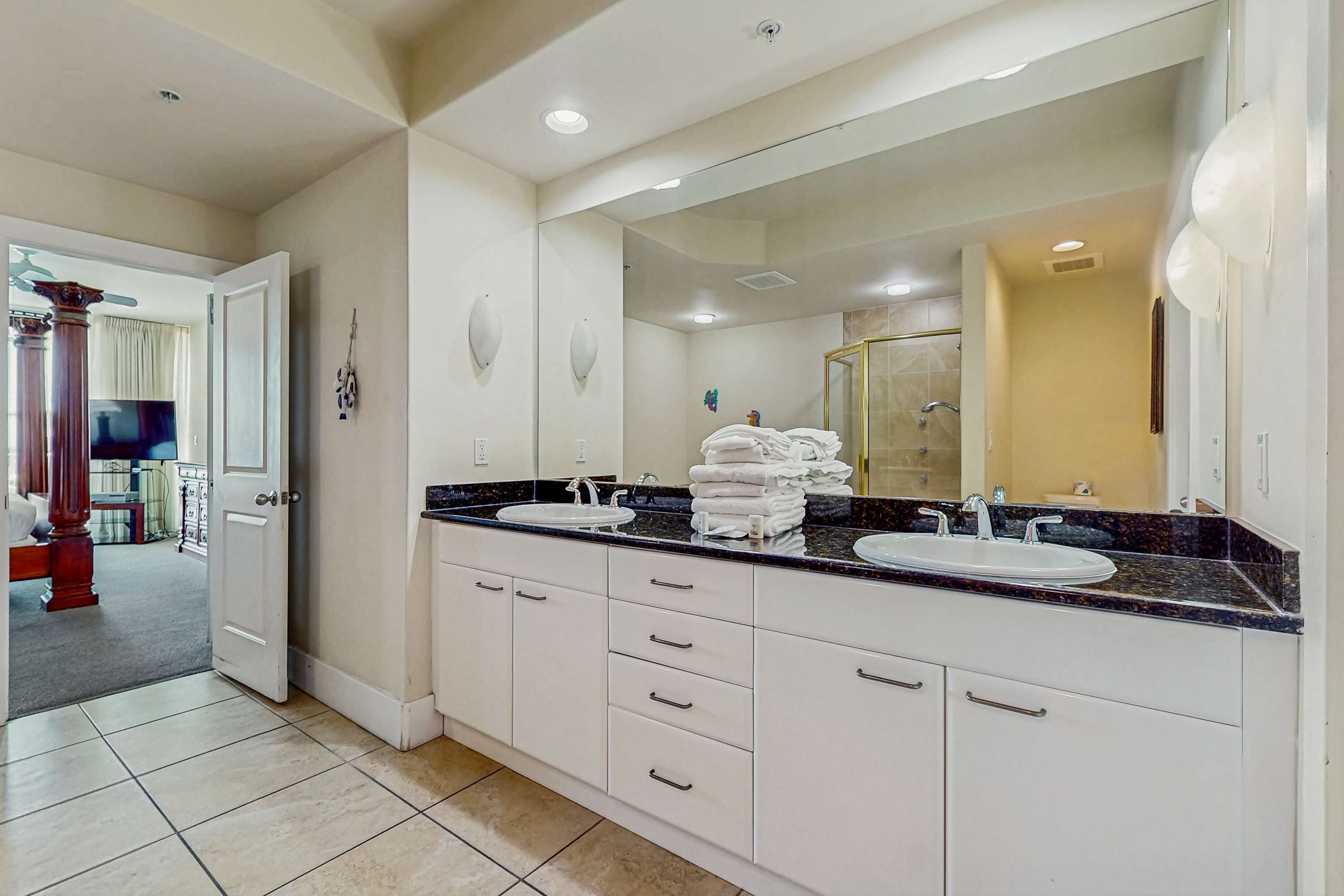 A bathroom with two sinks, a large mirror, and a shower area.
