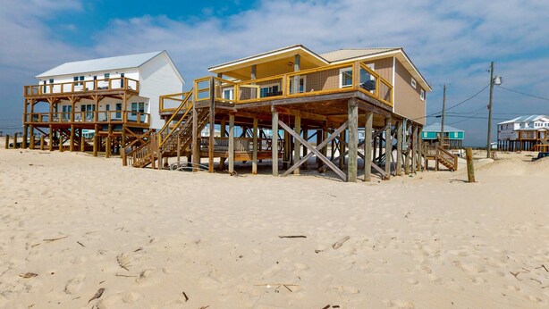 Une propriété située en bord de mer, dotée de structures en bois, notamment une maison et un bâtiment séparé avec un balcon.