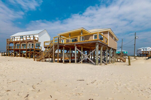 Une propriété située en bord de mer, dotée de structures en bois, notamment une maison et un bâtiment séparé avec un balcon.