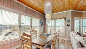 Ein Holzinterieur mit Esstisch, Stühlen, einer Couch und einem Kronleuchter.