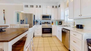 Una cocina moderna con armarios blancos, una mesa de comedor de madera y un horno empotrado.