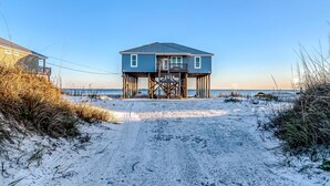 Ein Strandhaus mit Holzterrasse und freiem Blick auf den Ozean.