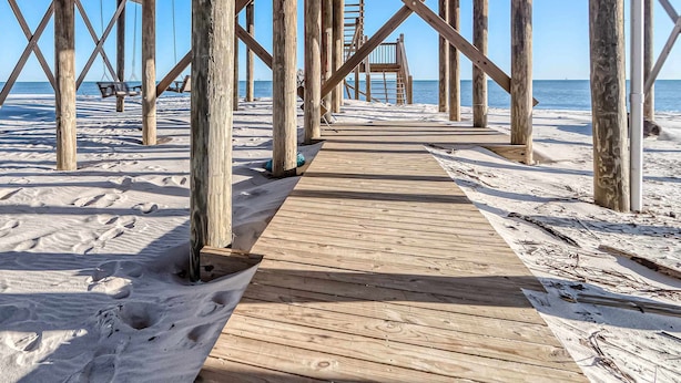Eine Holzstege führt zu einem Strand mit freiem Blick auf den Ozean.
