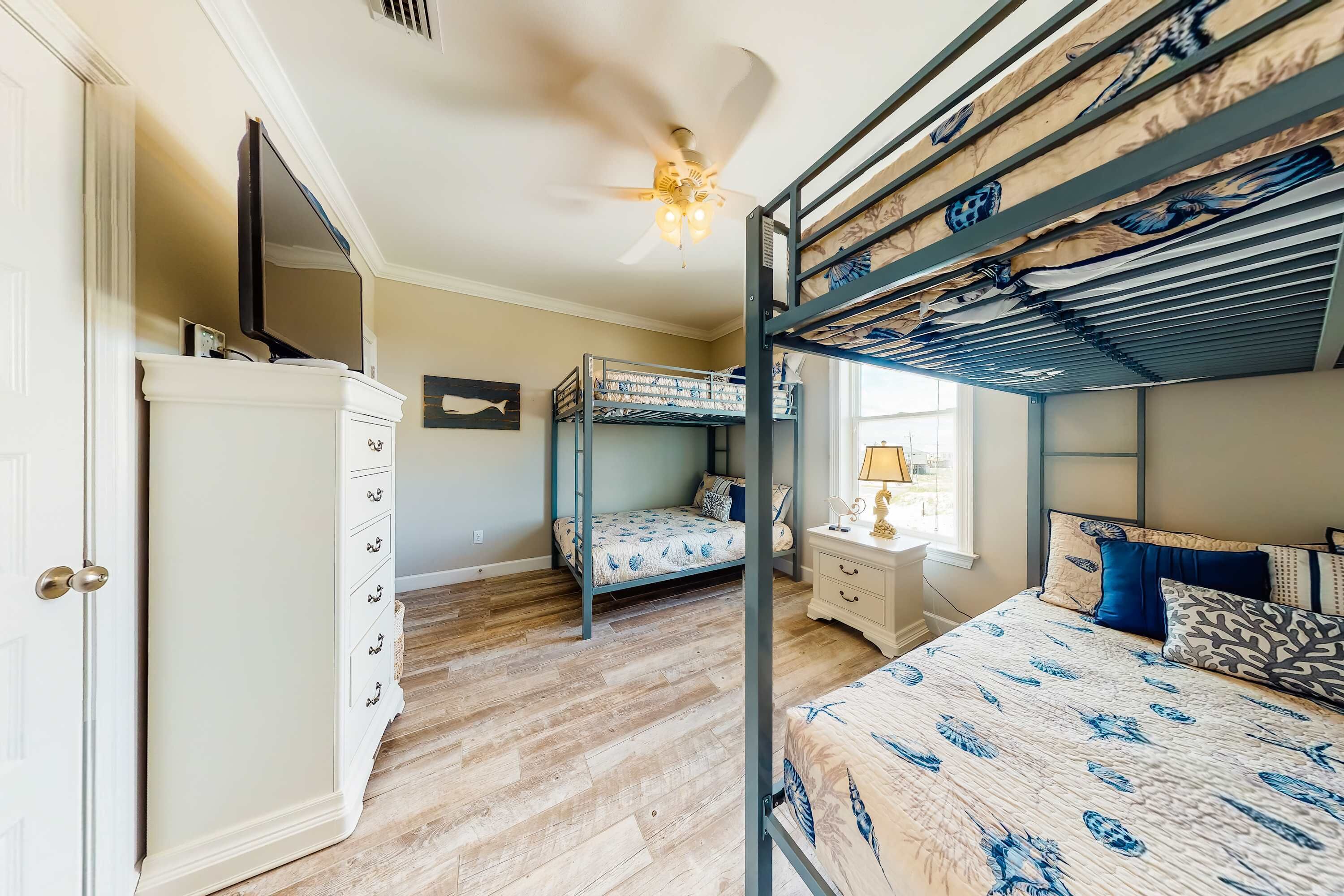 Une chambre avec un lit superposé, une commode, un ventilateur de plafond et une fenêtre.