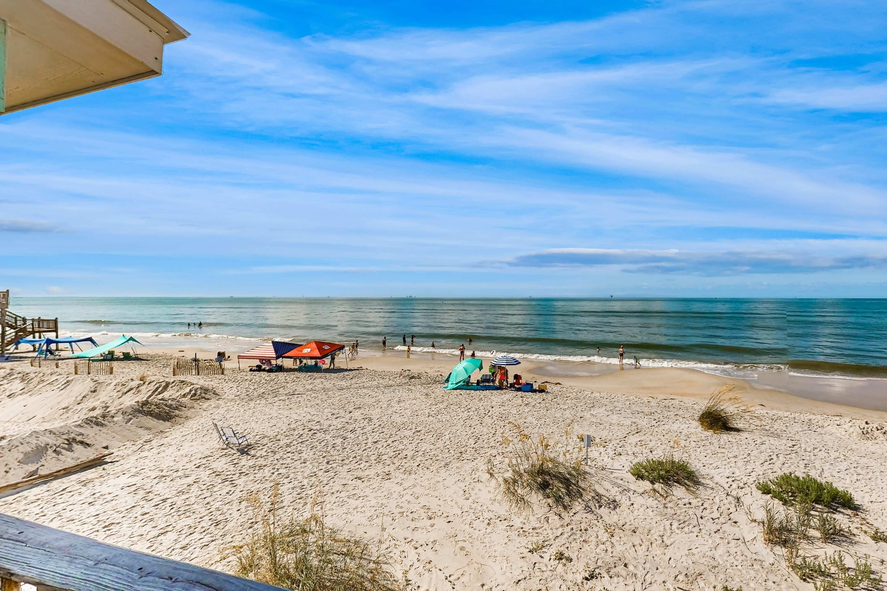 A beach with a wooden deck, beach umbrellas, and a lifeguard stand.