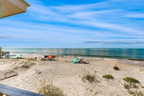 A beach with a wooden deck, beach umbrellas, and a lifeguard stand. - Dog-friendly beachfront home with spacious deck, amazing views of the Gulf (Dauphin Island)