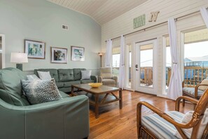 A living room with a sofa, armchairs, a coffee table, and a view of the outside. - Dog-friendly seaside home with WiFi, deck, amazing views, minutes from beach (Dauphin Island)