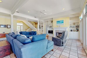 Ein geräumiges Wohnzimmer mit einem großen, blauen Ecksofa, einem Kamin und einer Treppe, die in eine andere Ebene führt.