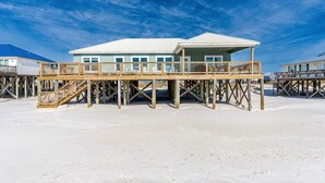 Una propiedad frente a la playa con una terraza de madera, un área cubierta y un edificio con varias ventanas.