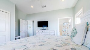 Un dormitorio con cama, televisor, cómoda y puerta.
