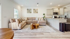 A modern living room with a sectional sofa, a wooden coffee table, and a kitchen area with built-in appliances. - Cozy townhome located near The Wharf concert and event venue! (Orange Beach)