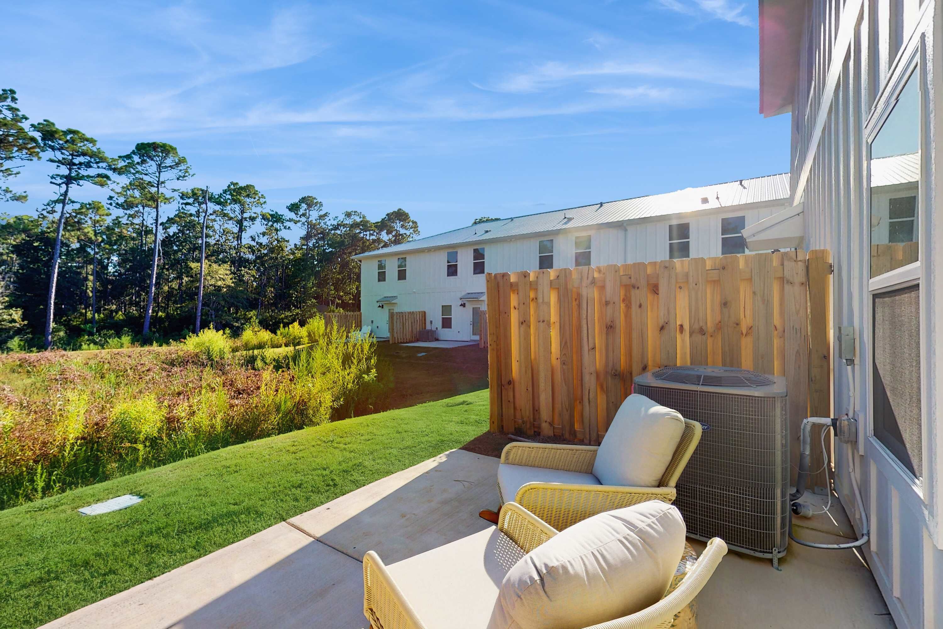 A patio with outdoor furniture, a wooden fence, and a building in the background.