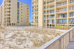 A multi-story hotel with balconies, a pool, and a sandy area. - Beachfront condo with pool, private balcony, & washer and dryer! (Orange Beach)