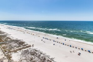 A beach with a long stretch of sand, a few umbrellas, and a clear view of the ocean. - Beautiful beachfront condo with hot tub, pool, sauna, tennis, gym, & balcony (Orange Beach)