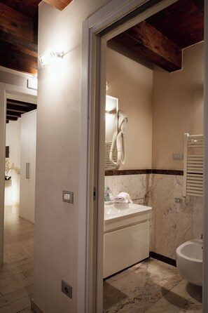 A bathroom with a marble floor, a white sink, a towel rack, and a bidet. - Piccola Venezia Room (Chioggia)