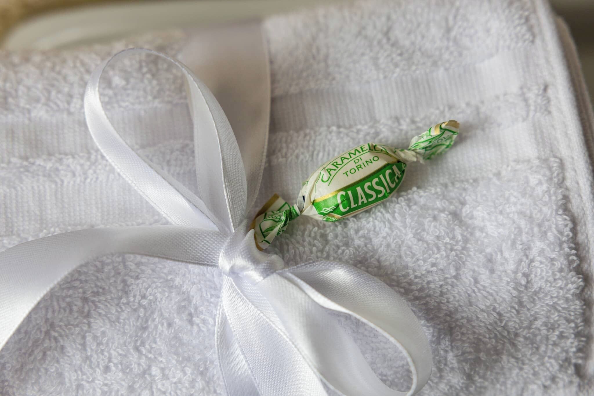 A white ribbon tied around a gift box with a green and white label.