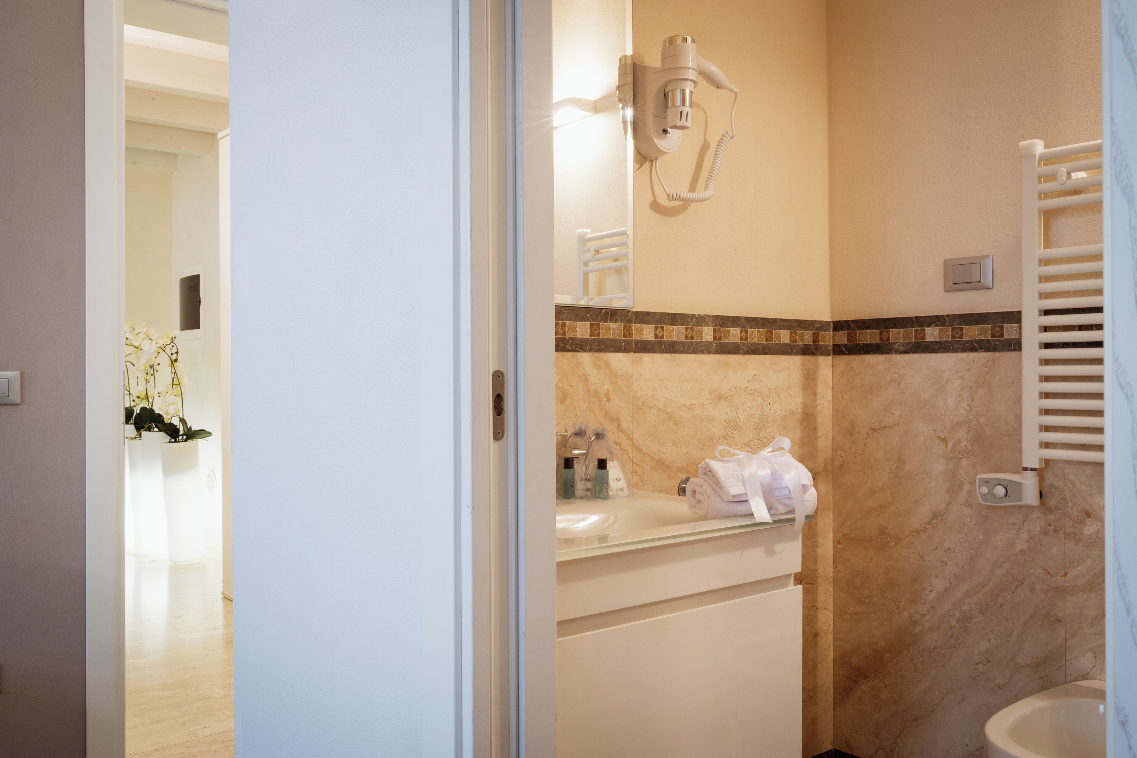 A bathroom with a sink, towel rack, and a hairdryer mounted on the wall.