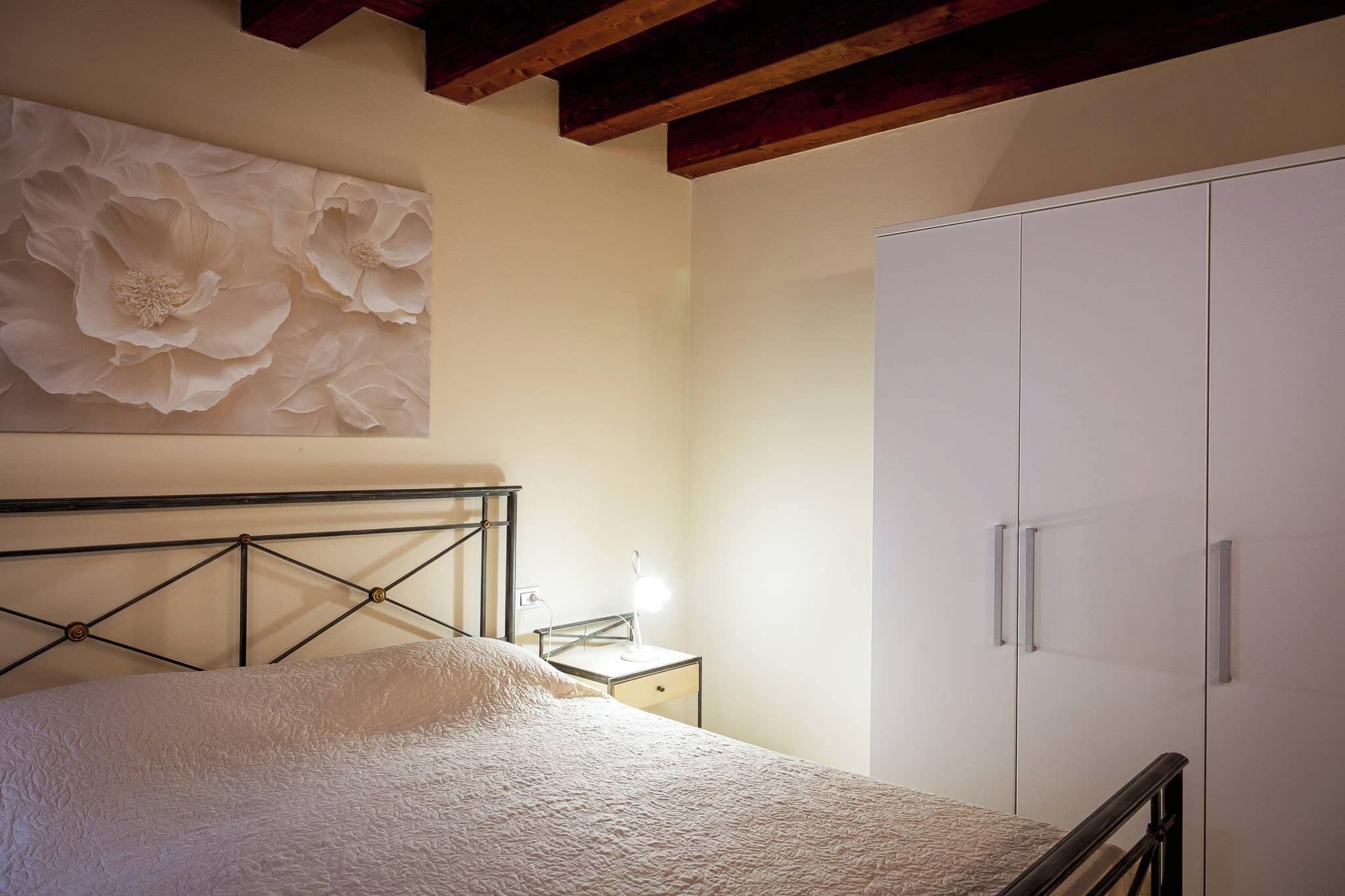 Un dormitorio con cama, mesita de noche, lámpara y armario.