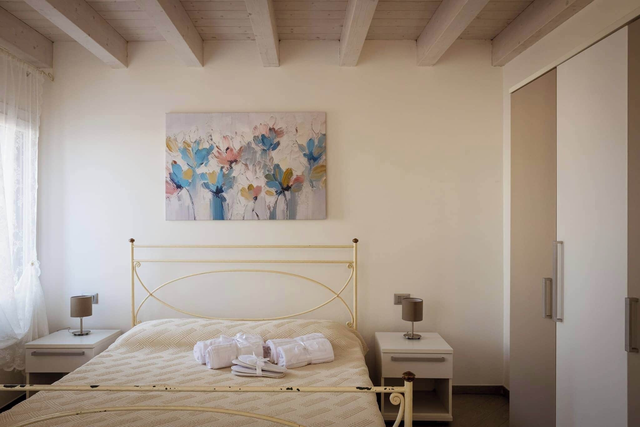 Un dormitorio con cama, dos mesitas de noche, un cuadro en la pared y un armario.