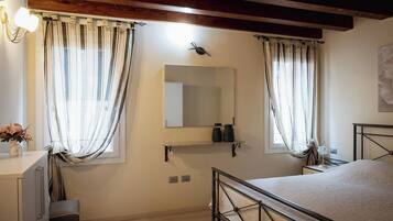 Un dormitorio con cama, mesita de noche, lámpara y un espejo en la pared.