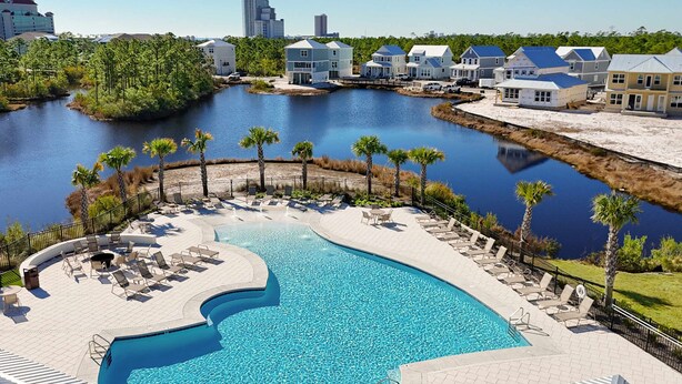 A swimming pool with lounge chairs, a waterfront view, and residential buildings.
