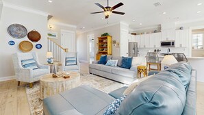 A living room with a sofa, armchairs, a coffee table, and a ceiling fan.